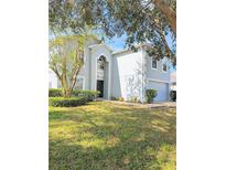 Charming two-story home with a manicured lawn, mature trees, and a light blue and white exterior paint scheme at 2131 Nicollett Way, Leesburg, FL 34748