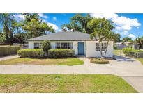 Charming single-story home with a well-manicured lawn, lush green bushes, and a blue front door at 2812 E Michigan St, Orlando, FL 32806