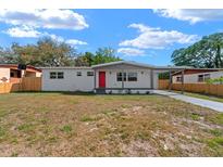 Charming single-story home with a bright red front door and carport, complemented by a well-kept front lawn at 5612 Meridian Way, Orlando, FL 32808
