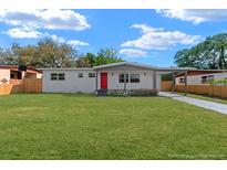 Charming single-story home boasts a vibrant red door and a lush green lawn at 5612 Meridian Way, Orlando, FL 32808