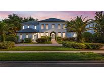 Stunning two-story home featuring lush landscaping, a symmetrical facade, and a welcoming arched entrance at 10849 Emerald Chase Dr, Orlando, FL 32836
