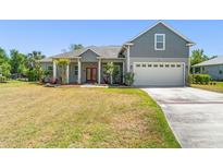 Charming two-story home with a well-manicured lawn, gray siding and a red front door at 1103 Lindley Cove Cir, Deland, FL 32724