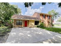 Charming two-story home with stone accents, a bright red front door, and a spacious driveway at 5518 Cretan Way, Winter Park, FL 32792