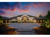 Breathtaking exterior view of estate home with paved driveway, tile roof, manicured landscaping and a colorful sunset sky at 570 Manor Rd, Maitland, FL 32751