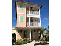 Three-story peach home boasting dual balconies and thatched roofing at 8001 Sand Bar Dr, Kissimmee, FL 34747