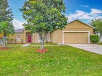 Charming single-story home with a well-maintained lawn, lush landscaping, and a vibrant red front door at 107 Carlisle Ct, Kissimmee, FL 34758
