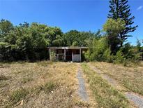 Single-story home featuring overgrown vegetation and driveway leading up to the house at 122 Laurel Dr, Sanford, FL 32773