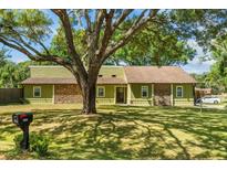 Charming home with a large tree in the front yard, showcasing a blend of wood and stone accents at 3790 Ne 22Nd Ave, Ocala, FL 34479