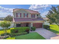 Charming two-story home with a well-manicured lawn, brick-paved driveway and mature landscaping at 4113 Longbow Dr, Clermont, FL 34711