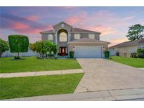 Two-story home featuring a well-manicured lawn and traditional architectural design with a driveway and attached garage at 4574 Ficus Tree Rd, Kissimmee, FL 34758