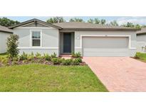 Charming single-story home with a two-car garage, brick driveway, and well-manicured lawn at 4713 Jasmine Cir, Leesburg, FL 34748