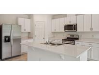 Bright kitchen features white cabinets, stainless steel appliances, a large island and quartz countertops at 4728 Jasmine Cir, Leesburg, FL 34748