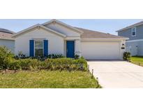 Charming single-story home with a well-manicured lawn and a bright blue front door at 6935 Dilly Lake Ave, Groveland, FL 34736