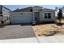 Charming single-story home with a two-car garage and brick paver driveway, showcasing modern design at 738 Pointe Emerson Blvd, Apopka, FL 32703