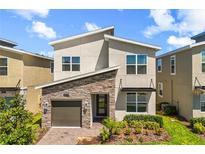 Modern two-story home featuring a stone facade, manicured lawn, and a one-car garage at 9179 Sommerset Hills Dr, Davenport, FL 33896