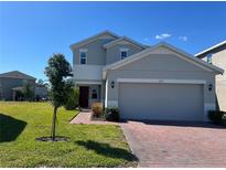 Two-story home featuring a well-maintained lawn, brick driveway, and an attached two-car garage at 1116 Myrtle Hammock Ln, Davenport, FL 33837