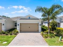 Charming home with a two-car garage, brick driveway, beautiful landscaping, and a mature palm tree at 2026 Key Bay Trl, Kissimmee, FL 34747
