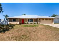 Charming single-story home features a silver metal roof, manicured lawn and a bright red front door at 2990 Mallard Dr, Deltona, FL 32738