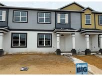 Two-story townhome featuring neutral colored siding, white trim, and a covered entryway at 628 Pothos St, Apopka, FL 32703