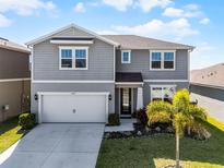 Charming two-story home featuring a two car garage, landscaped front yard, and grey siding at 7649 Ragusa Way, Clermont, FL 34714