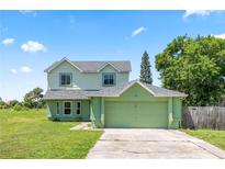 Two-story home features a two-car garage, fresh green paint, a gray roof, and a green lawn on a partly cloudy day at 905 Ocala Woods Ln, Orlando, FL 32824