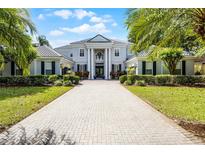 Stately two-story home with a columned entrance, gray exterior, manicured landscaping, and a paver driveway at 11014 Hawkshead Ct, Windermere, FL 34786
