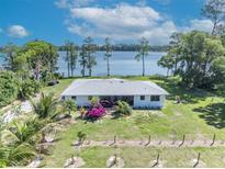 Charming single-story home featuring a picturesque lake view and lush landscaping at 7420 Lake Willis Dr, Orlando, FL 32821