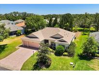 Lovely home with a brick driveway, well-kept lawn, mature trees, and a convenient three-car garage at 24104 Peekskill St, Leesburg, FL 34748