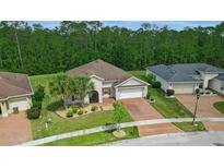 Inviting single-story home featuring a well-manicured lawn, brick driveway, mature landscaping, and charming architectural details at 3824 Gulf Shore Cir, Kissimmee, FL 34746