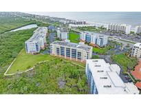 An aerial view shows the condo buildings and nearby scenery featuring the beach, trees, and waterways at 5300 S Atlantic Ave # 6-301, New Smyrna Beach, FL 32169