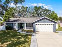 Charming single-story home with a well-manicured lawn, gray exterior and a two car garage at 15532 Kensington Trl, Clermont, FL 34711