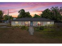 Charming single-story home featuring lush landscaping and a welcoming blue front door under a colorful sunset at 197 Flame Ave, Maitland, FL 32751