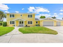 Bright yellow two-story home featuring a spacious lawn and attached two-car garage at 5224 Saint Regis Pl, Belle Isle, FL 32812