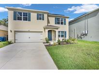 Two-story home with tan stucco, blue shutters, two-car garage, and manicured lawn at 1068 Brooklet Dr, Davenport, FL 33837