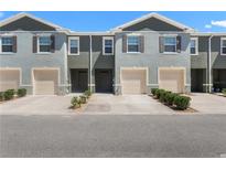 Charming townhomes featuring neutral exteriors, garages, and manicured landscaping under a clear blue sky at 1121 Blue Jay Dr, Davenport, FL 33837