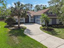 Charming blue home featuring a spacious driveway, well-manicured lawn, and beautiful palm trees at 1570 Westover Loop, Lake Mary, FL 32746