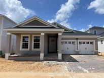 Charming single-story home featuring a two-car garage and craftsman details including brick trim and a covered entry at 16759 Muskgrass Dr, Winter Garden, FL 34787