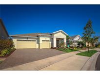 Inviting home exterior features a two-car garage, paver driveway, and beautifully landscaped yard under a clear blue sky at 2458 Dream Home Ct, St Cloud, FL 34772