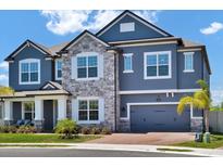 Charming two-story home with stone accents, blue siding, lush landscaping, and a convenient two-car garage at 2628 Cedar Shake Ct, Oviedo, FL 32765