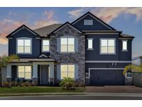 Charming two-story home featuring a stone facade and an attached two-car garage, showcasing modern architectural design at 2628 Cedar Shake Ct, Oviedo, FL 32765