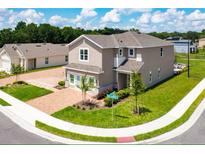Two-story home with attached garage, brick paved driveway, professionally landscaped lawn, and beautiful corner lot at 402 Cool Summer Ln, Davenport, FL 33837