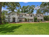 Charming two-story home with a lush green lawn and mature trees surrounding the property at 450 Andrews Dr, Longwood, FL 32750