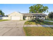 Charming single-story home with an attached garage, covered porch, and well-maintained landscaping at 5547 Kingswood Dr, Orlando, FL 32810