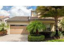 Charming two-story home with a well-manicured lawn, palm trees, and a two-car garage at 9895 Winnington St, Orlando, FL 32832