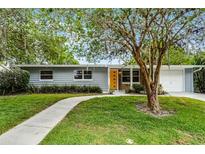 Charming single-story home featuring a well-manicured lawn, inviting walkway, and bright orange front door at 117 Exeter Ave, Longwood, FL 32750