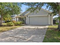 Charming single-story home featuring a gray exterior, two-car garage, and well-maintained landscaping at 634 Chadbury Way, Kissimmee, FL 34744