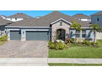 Beautiful single-Gathering home with a paver driveway, stone accents, and a well-manicured lawn at 690 Blue Citrus Ln, Minneola, FL 34715