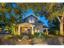 Charming two-story home featuring a brick walkway, front porch, and mature trees at 13 Hill Ave, Orlando, FL 32801