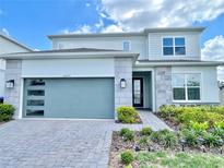 Two-story home with a modern garage door, stone accents, manicured landscaping, and a paver driveway at 10275 Park Estates Ave, Orlando, FL 32836