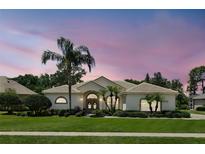 Charming single-story home with lush landscaping, palm trees, and a tile roof at dusk at 216 Hammock Oak Cir, Debary, FL 32713